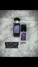 This video provides a close-up comparison of the SOINS 'Happiness' perfume line. It features a full-sized bottle and a smaller travel spray, both showcasing the brand's signature purple label design. Arabic text overlays indicate this is a fragrance review ('مراجعات عطور') and a product showcase ('عرض'), suggesting a focus on the scent's qualities. by @soins_sa with Original Sound by soins_sa
