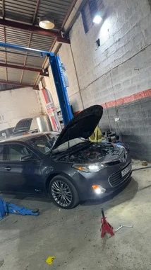 This video provides a quick tour of Wasta Hawkar's auto repair garage. It features a black Toyota Avalon with its hood open on a blue Autokin lift, alongside another black BMW. The camera pans across the workshop, showcasing the vehicles and equipment in a well-lit, industrial space. by @hawkar_service with Original Sound by hawkar_service