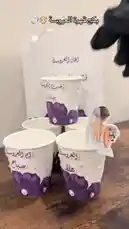 Discover how to create personalized wedding cups for your big day! This step-by-step guide shows you how to decorate paper cups with elegant purple flowers, pearls, and custom Arabic calligraphy for names like 'Rafah' and 'Saba'. Perfect for a modern, stylish celebration. by @r200an with original sound