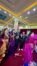 Witness a vibrant traditional dance performance featuring women in ornate purple and magenta costumes adorned with gold accessories. Dancers gracefully move across a red carpeted hall with decorative pillars and red curtains, surrounded by guests in formal attire, including men in black suits and traditional headwear. The festive atmosphere suggests a wedding or cultural event, showcasing heritage through synchronized choreography and elaborate folk costumes. by @artvideo.me with artvideo.me by Original Sound