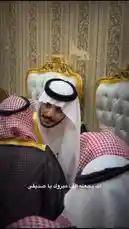 This intimate video captures a group of men dressed in traditional Saudi attire, including white thobes, red-and-white checkered shemagh scarves, and black agal headbands. They are seated in a luxurious room with ornate gold-trimmed chairs and patterned wallpaper, suggesting a formal meeting or social gathering. One man stands and smiles warmly at the camera, showcasing the intricate details of his clothing, such as the gold embroidery on his black bisht robe. The atmosphere is one of cultural pride and sophistication. by @karim.alsaleh with karim.alsaleh by Original Sound