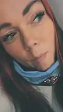 In this intimate close-up, Zagvik shares a moment from her day. She smiles warmly at the camera, showcasing her long dark hair with red highlights, striking blue eyes, and a light blue neck gaiter. Her expressive face and engaging presence create a personal connection with viewers. by @zagvik with zagvik by Contains: Beez In The Trap - Nicki Minaj