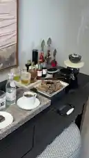 This stylish video showcases a beautifully arranged black table with coffee, chocolates, incense, and a collection of perfumes. The camera pans across the elegant setup, highlighting details like ornate glass bottles and a smoking incense burner. The accompanying Arabic music adds a sophisticated and relaxing ambiance. by @bee.8907 with Original Sound by bee.8907