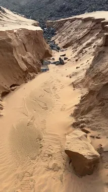 This captivating footage takes you on a journey through a striking desert landscape where golden sand dunes meet rugged black rock formations. A local explorer, dressed in traditional attire, guides viewers through this unique geological wonder, showcasing its scale and beauty. by @manahi.20 with manahi.20 by Original Sound
