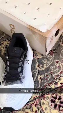 A close-up showcase of a new pair of white and black On Cloud X running shoes being unboxed and displayed on a patterned rug. The video highlights the shoe's design details, including the mesh upper, lacing system, and branding. by @absi_fashion with absi_fashion by Contains: El Youm - Ahmed Saad , Vidojean X Oliver Loenn