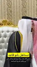 In a luxurious room adorned with ornate wallpaper and elegant gold-trimmed chairs, a man dressed in a traditional black thobe with golden trim shares a warm, friendly moment with another man in a red-and-white checkered keffiyeh. They engage in close conversation, smiling and gesturing animatedly, creating an atmosphere of respect and camaraderie. The scene captures a genuine interaction between individuals in formal attire, set against a backdrop of opulent decor. by @karim.alsaleh with karim.alsaleh by Original Sound