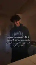 A young man, identified as Badr Al-Qahtani, is seen laughing heartily in a dimly lit kitchen. He is wearing a dark hoodie and has curly hair. The Arabic text overlay humorously suggests he is trying to be cool but fails because of his laughter. The audio captures his genuine amusement, creating a relatable and lighthearted moment. by @cviioul with Original Sound by cviioul