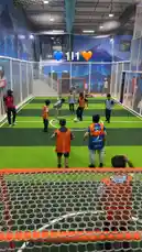 Watch kids enjoying a lively indoor soccer game in a modern sports facility. This energetic scene captures children actively playing, passing the ball, and celebrating goals under bright lights. The vibrant orange and blue jerseys add to the fun atmosphere of this youth sports event. by @gioco_23 with Original Sound by gioco_23