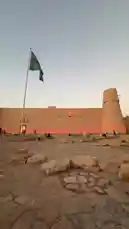 Experience the majestic Al-Ula Fort illuminated under a twilight sky, proudly flying the Saudi flag. This scenic view captures the essence of national pride, heritage, and culture, set against a backdrop of traditional architecture and a vibrant sunset. by @hamed_aldaban with original sound