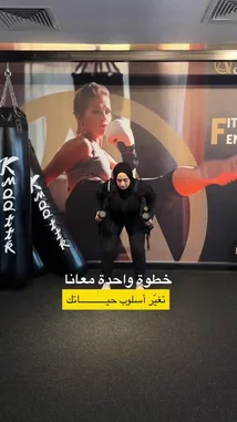 In this instructional fitness clip from Active Circle, a woman demonstrates the proper form for a kettlebell exercise. She performs a kettlebell swing with focused concentration, showcasing a common strength training movement. The setting is a modern gym with fitness branding visible in the background. Arabic text overlays identify the exercise as 'Kettlebell Swing' and 'Full Body Workout'. This visual guide provides clear steps for viewers looking to learn this effective workout. by @activecircle with Original Sound by activecircle