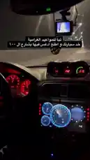 A first-person view from inside a car during a night drive. The dashboard features custom gauges with red, blue, and green illumination, including a prominent tachometer. An Arabic text overlay reads 'This is my car, I bought it for 1000 and fixed it myself.' A dashcam is visible on the windshield. by @wolfzzz3 with Original Sound by wolfzzz3