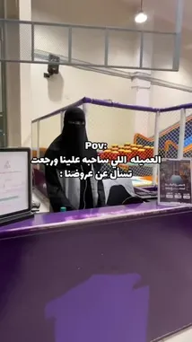 A woman in a black niqab stands behind the purple counter of a kids' play area, likely a bouncy castle or soft play gym. She is speaking with someone off-camera, possibly a parent. The Arabic text overlay translates to 'POV: The employee who is tired of being asked to open the door.' The conversation seems to be about a child named Ahmad who is being told to go play inside. This relatable moment captures the everyday challenges faced by staff in family entertainment venues. by @gioco_23 with Original Sound by gioco_23