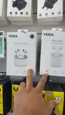 A close-up product showcase from SIMPLE STORE 🤳🏼⚡️ highlights two models of FEIDA Airbuds: the 'Airbuds Pro 2' and the standard 'Airbuds'. A hand points out the key differences on the packaging, including the 'Pro' designation and 'True Wireless Stereo' feature. The speaker in Arabic discusses the availability of these two editions, noting their popularity and unique features like 'Ripple', which may refer to a sound profile or design element. by @power.ch01 with Original Sound by power.ch01