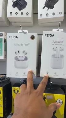 A close-up product showcase from SIMPLE STORE 🤳🏼⚡️ highlights two models of FEIDA Airbuds: the 'Airbuds Pro 2' and the standard 'Airbuds'. A hand points out the key differences on the packaging, including the 'Pro' designation and 'True Wireless Stereo' feature. The speaker in Arabic discusses the availability of these two editions, noting their popularity and unique features like 'Ripple', which may refer to a sound profile or design element. by @power.ch01 with Original Sound by power.ch01