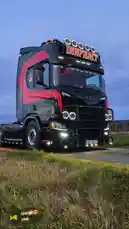 This dynamic compilation showcases Zagvik's impressive black and red INNFRKT Scania truck from multiple angles, including stunning dusk shots and animated renderings. The video features close-ups of its custom LED lights, grille guard, and 'INNFRKT' branding. It transitions to a lifestyle segment with a woman, presumably Zagvik, wearing a face covering with the same truck design, highlighting a personal connection to the brand. The final scenes present artistic interpretations of the truck in various settings, demonstrating the blend of real-world customization and creative digital art. by @zagvik with Siren🌄🤩 by Jolmh