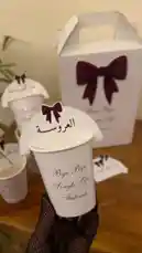 A close-up showcase of elegant white party cups and a matching gift box, all branded with 'Bye Bye Single Life' and Arabic text 'العروسة' (The Bride). This stylish setup, presented by متجر ريزن تبوك, is perfect for a bridal shower or bachelorette party, highlighting the celebratory theme with coordinated design elements. by @r200an with original sound