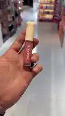 A first-person view of a person testing the 'MyHearts' brand lip gloss in a beauty store. The video shows the application of a pinkish-red, glittery liquid lipstick onto the back of their hand, followed by a close-up of the product tube revealing the shade name 'Roseberry'. The setting is a well-lit cosmetics boutique with various products on display. by @butik.mariya with ♥️♥️♥️♥️♥️! by Contains: Ana Mosh Anany - Amr Diab