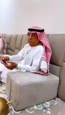 This video captures a traditional social gathering of men in Kuwait. Dressed in white thobes and red-and-white checkered ghutras, they relax on a large sofa and the floor, chatting and using their phones. The setting is a modern living room with a patterned carpet and contemporary furniture, showcasing a blend of cultural tradition and modern lifestyle. by @fahaad0465 with سجة سنافي📻 by jt_hx