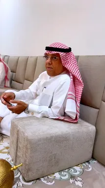 This video captures a traditional social gathering of men in Kuwait. Dressed in white thobes and red-and-white checkered ghutras, they relax on a large sofa and the floor, chatting and using their phones. The setting is a modern living room with a patterned carpet and contemporary furniture, showcasing a blend of cultural tradition and modern lifestyle. by @fahaad0465 with سجة سنافي📻 by jt_hx