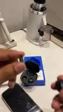 A close-up demonstration of unboxing and using black wireless earbuds with a magnetic charging case. The video shows how to open the case, handle the earbuds, and features a unique detachable microphone component. A speaker explains the practical use of the small, removable mic piece, which can be magnetically attached to clothing for discreet recording during filming, ensuring the microphone remains hidden while providing clear audio. by @power.ch01 with Original Sound by power.ch01