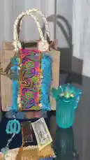 A beautifully styled flat lay of a handmade tote bag and accessories by Joy Narcissus. The jute bag features vibrant blue tassels, intricate embroidery, and gold Arabic calligraphy. It is displayed alongside a matching turquoise glass vase, prayer beads, and decorative papers, creating a stunning showcase of artisanal craftsmanship. by @joy.narcissus with Original Sound by joy.narcissus