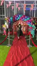 A vibrant circus-themed event hosted by جوكو للترفيه features a red carpet runway where participants strut in a variety of costumes. From elegant dresses and playful clown attire to superhero and fantasy outfits, the models showcase their unique styles under colorful balloon arches and festive decorations. by @gioco_23 with Original Sound by gioco_23