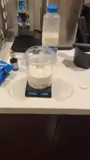 In this concise kitchen tutorial, a person demonstrates the precise method of measuring milk using a digital scale. The process begins with an empty container on the scale, which is then zeroed out. Milk is poured into the container from a carton until the desired weight is reached, showcasing a foolproof technique for accurate ingredient measurement. This practical guide is ideal for anyone looking to improve their cooking precision, especially for recipes requiring exact proportions. by @alysf90 with Original Sound by alysf90