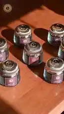 This video showcases the elegant presentation of Shams Line Perfumes' luxury fragrance collection. It begins with a display of several ornate glass jars with gold lids arranged on a wooden surface, highlighting the brand's sophisticated packaging. A hand then picks up one jar, revealing its contents—small black pieces, possibly agarwood chips used in perfume making. The scene transitions to a woman wearing a black hijab, holding a golden incense burner with smoke rising from it, suggesting the use of fragrant materials like oud or bakhoor. The overall aesthetic emphasizes luxury, tradition, and the art of scent. by @shamslinep with shamslinep by Original Sound