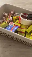 A close-up view of a gift basket filled with colorful snack boxes like Fruitella and Pop Rocks. The camera then pans to reveal a white box containing multiple pink and red packages labeled 'عيد سعيد' (Happy Eid) in Arabic, suggesting a festive holiday gift set. by @rubaaomaar with Original Sound by Contains: Color Mixing - Dance Trend