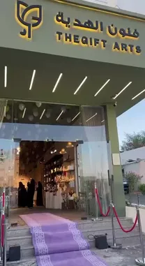 This video provides a tour of 'THE GIFT ARTS', a store specializing in gifts, flowers, and event styling. It begins with an exterior shot of the modern storefront and then moves inside to showcase beautifully arranged shelves of potted plants and floral bouquets. The tour continues to a dedicated event space, where elegant green glass serving bowls filled with snacks are displayed on white stands. Finally, a person in a white uniform is seen preparing a drink using a cocktail shaker, suggesting the store offers services like coffee or mocktail preparation for events. by @gift_arts1 with gift_arts1 by Original Sound