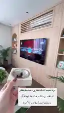 في هذا المشهد، تُظهر منيرة الغصن منزلها الفاخر والمُصمم بذوق رفيع. تُركّز الكاميرا على غرفة معيشة واسعة ذات إضاءة طبيعية ساطعة، تضم أثاثًا عصريًا وألوانًا ناعمة، مع تلفزيون مثبت على الحائط يعرض محتوى باللغة الإنجليزية. يُلاحظ وجود نباتات داخلية وديكورات أنيقة، مما يعكس جوًا دافئًا ومريحًا. تُظهر منيرة أيضًا حاملًا خشبيًا صغيرًا يحتوي على قطعة فنية، بينما تُظهر النصوص العربية على الشاشة أنها تتحدث عن أسلوبها في التصميم الداخلي وتحب الألوان الزاهية والأسلوب البسيط. المشهد يُبرز الذوق الرفيع في التصميم الداخلي وروح الراحة والجمال. by @moneeragh with Original Sound by moneeragh