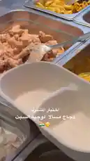 A close-up look at various protein meal prep options being served. A ladle scoops a portion of yellow-coated chicken pieces from a stainless steel container into a white takeout bowl. Other containers with different protein types and sides are visible in the background, showcasing a variety of healthy meal choices. by @proteinz_sa with original sound