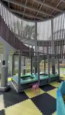 A tour of a modern indoor playground featuring a trampoline, a large ball pit filled with colorful balls, and a spiral slide. The space has a unique design with vertical slats and a checkered floor. by @moneeragh with Original Sound by moneeragh