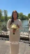 A joyful couple celebrates their wedding day with a candid first video together as newlyweds. Lisa, radiant in her white beaded dress and holding a bouquet of white roses, shares her excitement with the camera. Her husband, Niko, joins her, and they both express their happiness. The text overlay 'POV: das erste Video nach dem Standesamt' confirms this is their first video after the civil ceremony. by @liisa.niiko with Original Sound by liisa.niiko