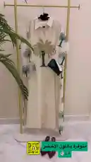 Watch as a beautifully crafted white dress with a striking palm tree design takes center stage. This elegant piece features a prominent gold-embellished palm tree on the front, complemented by a repeating green palm tree pattern on the sleeves and side panels. The dress is displayed on a modern gold hanger, highlighting its sophisticated silhouette and unique details. Perfect for summer fashion inspiration. by @needle_t with original sound