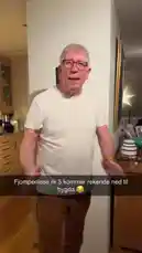 An older man in a white t-shirt demonstrates how to hang a new 'Pottaslekir' wall calendar, which features a humorous illustration of a gnome. He shows the back of the calendar and then proceeds to hang it on a white wall, providing a simple tutorial for viewers. by @monajohanneh with monajohanneh by Original Sound