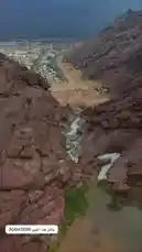 This video captures a breathtaking aerial view of a powerful waterfall cascading down a rugged mountain slope. The camera follows the water's path as it tumbles over rocks and boulders, eventually flowing into a river below. In the background, a town is visible nestled in the valley, contrasting with the wild beauty of the surrounding landscape under a clear blue sky. by @y_alkhmsan with Original Sound by Contains: Enduring Hope - Daniel Deuschle