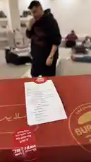 A man excitedly presents a large red 'Burgerizza' box to his friends in a living room. After some playful interaction, he opens it to reveal multiple burgers and tacos inside, which he then shares with everyone. by @d7oomysnap with d7oomysnap by Original Sound