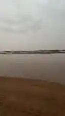 This captivating footage captures the tranquil beauty of a vast desert landscape during twilight. The camera glides across a wide, flat expanse of wet sand, reflecting the soft, golden hues of the setting sun breaking through the clouds. Sparse, wind-swept trees dot the horizon, silhouetted against the dramatic sky. The scene evokes a sense of peace and isolation, showcasing nature's quiet majesty in a remote location. by @manahi.20 with manahi.20 by Original Sound