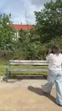 A woman celebrates her birthday outdoors on a park bench. She pops a bottle of champagne, creating a festive spray, while smiling at the camera. The moment is captured in a celebratory mood. by @mimi6kids with Original Sound by Contains: It's Raining Men (Single Version) - The Weather Girls