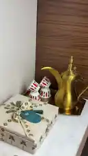 This elegant video showcases a beautifully styled table setting featuring traditional Arabian elements. A hand in a white glove arranges ornate perfume bottles, a golden Arabic coffee pot (dallah), and a tray of frankincense. The scene transitions to reveal a box of dates and a collection of luxury perfumes, all presented in a sophisticated manner. by @bee.8907 with Original Sound by bee.8907