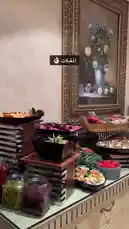 Watch a stunning buffet spread come together in this behind-the-scenes look at event catering by نجوم المستوى لتنظيم الحفلات ✨️. The camera pans across a lavish table laden with colorful salads, creatively carved fruit bowls, sushi boats, and gourmet appetizers, all meticulously arranged on elegant tiered stands. A server in white gloves is then seen carefully placing a decorative centerpiece of intricately cut vegetables, showcasing the attention to detail and artistry involved in creating a memorable dining experience for a special occasion. by @levelstars7 with Original Sound by levelstars7