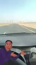 This first-person perspective video captures a journey down a long, straight highway through a vast desert landscape during a sandstorm. An animated character is superimposed on the dashboard, reacting to the conditions. The sound of the car engine and wind is prominent, and Arabic speech describes the 'sand rain' they are experiencing. by @om-5p with Original Sound by om-5p
