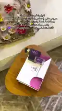 A stylish display of SOINS Happiness beauty products, including a perfume bottle and nail polish, presented on a wooden table with floral decor. The Arabic text overlay highlights the brand's philosophy of happiness, fragrance, and self-care. by @soins_sa with Original Sound by soins_sa