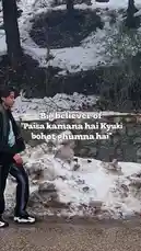 A young man walks along a snow-lined path, seemingly lost in thought. The text overlay 'Big believer of "Paisa kamana hai Kyuki bohot ghumna hai"' suggests a philosophy of travel and adventure being driven by financial necessity. This short clip captures a moment of contemplation during a journey. by @lil.ishhhh with Original Sound by lil.ishhhh