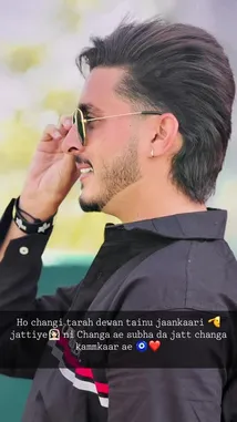 A man with dark hair, a beard, and sunglasses strikes a confident pose in a black collared shirt with red and white stripes. He adjusts his round gold-rimmed sunglasses while smiling slightly, showcasing a modern and stylish look. by @officialaman08 with Original Sound by officialaman08