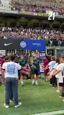 In a vibrant pre-match atmosphere, Inter Milan players stride onto the pitch, shaking hands with young ball kids in a traditional gesture before kickoff. Dressed in their distinctive blue patterned jerseys sponsored by Qatar Airways, the squad moves through a tunnel entrance into the stadium. The stands are filled with fans waving flags and cheering, creating an electric ambiance. This moment captures the anticipation and team spirit just before the start of an Inter Milan game. by @interofficial with Original Sound by interofficial