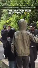 A group of men, including one in a black tracksuit and another in a green hooded jacket, walk along a wet path next to a large hedge. They are greeted by others, shaking hands and interacting warmly. Some carry bags and phones, suggesting they might be arriving at an event. The atmosphere is friendly and energetic. by @ligue1 with Original Sound by ligue1