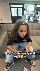 This comedic skit by IZER follows a classic sibling rivalry. A young girl, playing the 'bad brother,' playfully harasses her younger sister in various settings, including a living room, a park bench, and a hallway. The sister's exasperated reactions and the 'bad brother's' mischievous behavior create a humorous dynamic. The French text overlay 'Pov: Ce mauvais grand frère 😟💙' translates to 'POV: This bad older brother 😟💙', setting the comedic tone. by @izerflyy with Original Sound by izerflyy