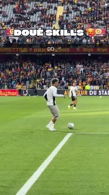In a packed stadium, a soccer player in a white jersey attempts an impressive skill move near the sideline. The crowd watches intently as he juggles the ball, showcasing his talent. The on-screen text 'DOUÉ SKILLS' adds a playful challenge to the moment. by @ligue1 with Original Sound by ligue1